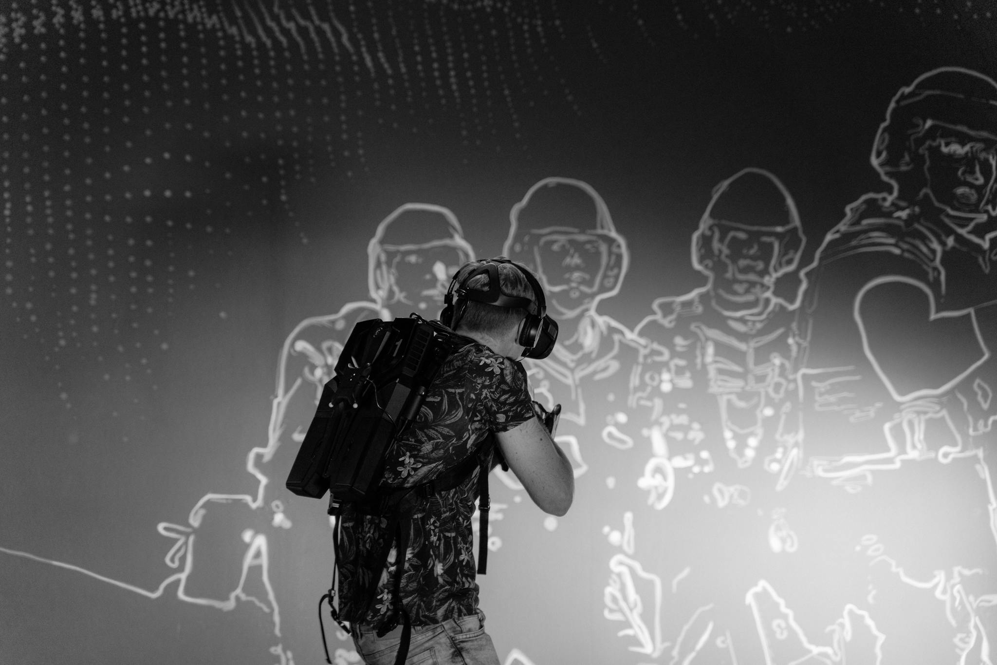 Black-and-white photo of a man using virtual reality equipment indoors.